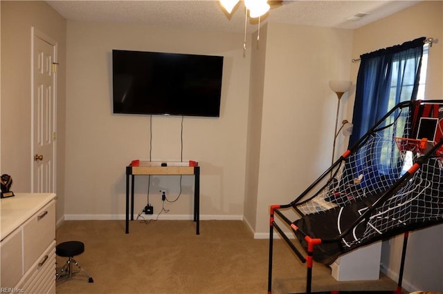 recreation room featuring light colored carpet, a ceiling fan, and baseboards