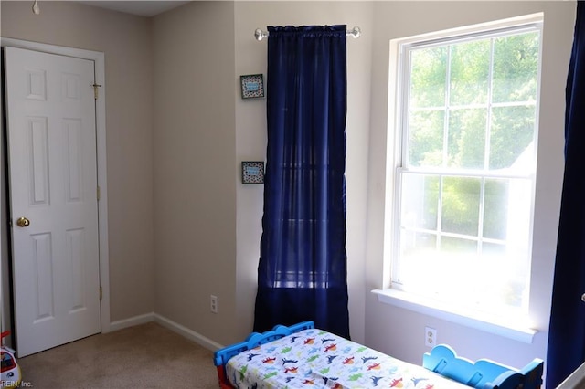 carpeted bedroom featuring multiple windows and baseboards