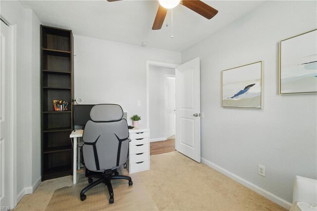 office with baseboards, a ceiling fan, and light colored carpet