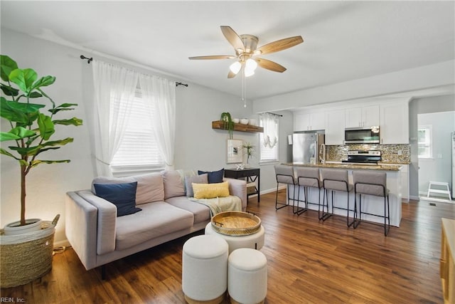 living room featuring baseboards, ceiling fan, and dark wood finished floors