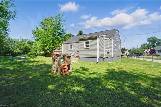 back of house featuring fence, a shingled roof, a lawn, and crawl space