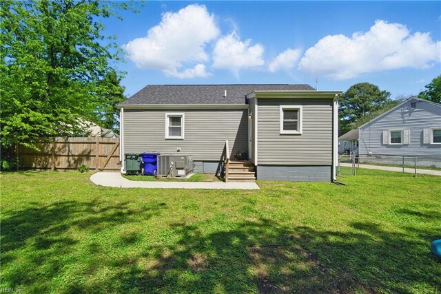 rear view of house with a lawn, central AC, and fence