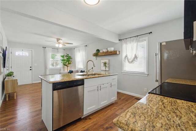 kitchen with an island with sink, dark wood-type flooring, white cabinets, a sink, and stainless steel appliances