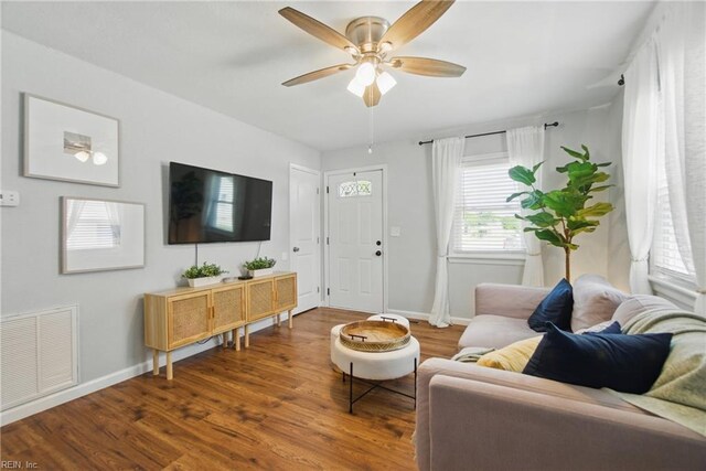 living area featuring baseboards, ceiling fan, dark wood-style flooring, and visible vents
