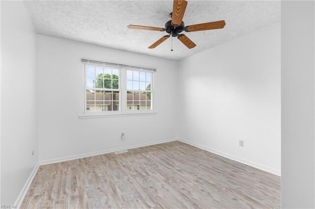 empty room featuring baseboards, a textured ceiling, wood finished floors, and visible vents
