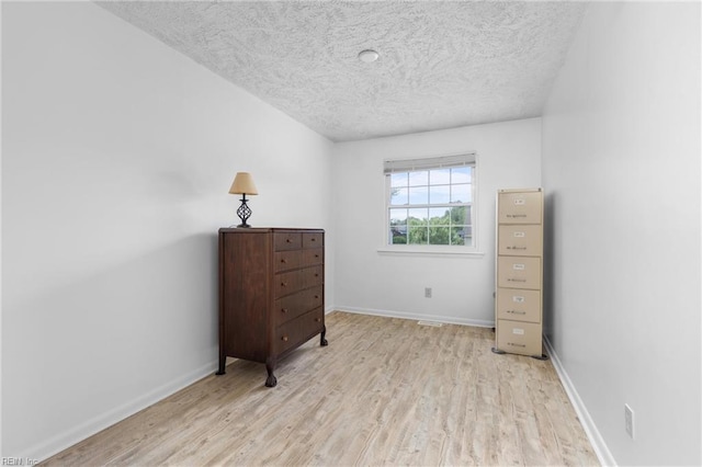 bedroom featuring a textured ceiling, baseboards, and light wood-style flooring