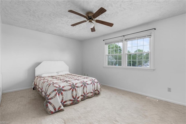 carpeted bedroom featuring baseboards, a ceiling fan, a textured ceiling, and visible vents