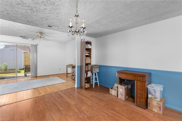 interior space featuring visible vents, wood finished floors, baseboards, a textured ceiling, and ceiling fan with notable chandelier