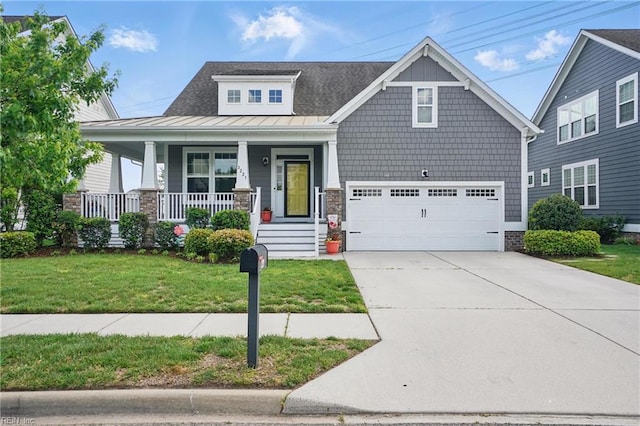 craftsman-style house featuring a front lawn, a standing seam roof, concrete driveway, an attached garage, and a porch