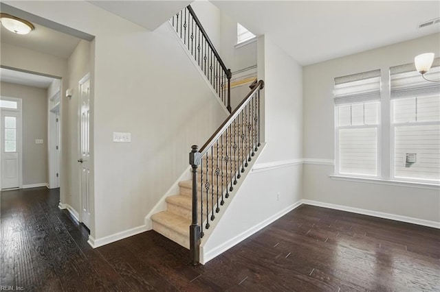 stairway with baseboards, visible vents, and wood finished floors