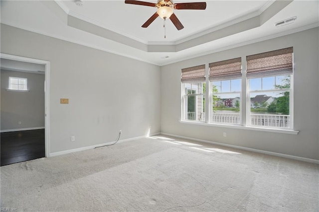 carpeted spare room with baseboards, ornamental molding, ceiling fan, and a tray ceiling