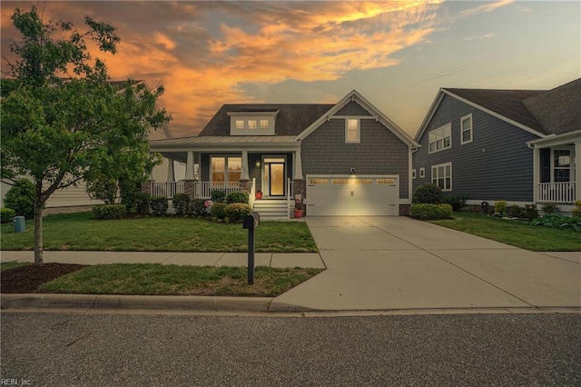 craftsman inspired home featuring a porch, a front lawn, concrete driveway, an attached garage, and stone siding
