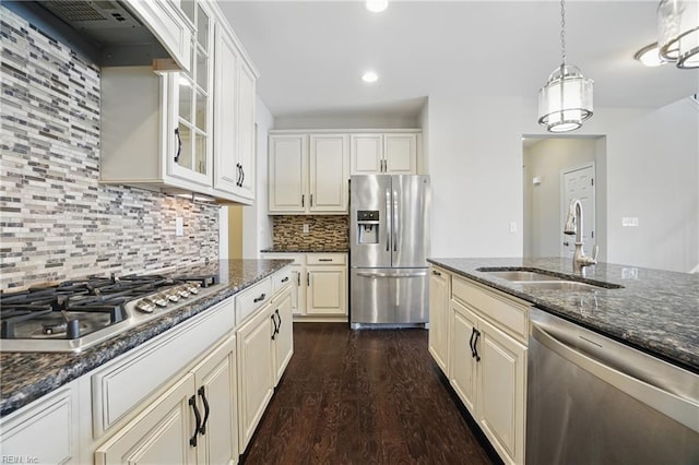 kitchen featuring glass insert cabinets, wall chimney exhaust hood, a sink, dark wood finished floors, and stainless steel appliances