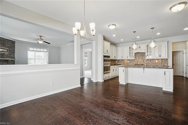kitchen with dark wood-style flooring, dark countertops, a breakfast bar area, decorative backsplash, and glass insert cabinets