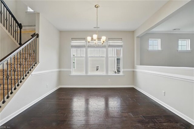unfurnished dining area featuring stairway, baseboards, wood finished floors, and a chandelier