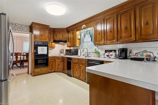 kitchen featuring backsplash, brown cabinetry, black appliances, and light countertops