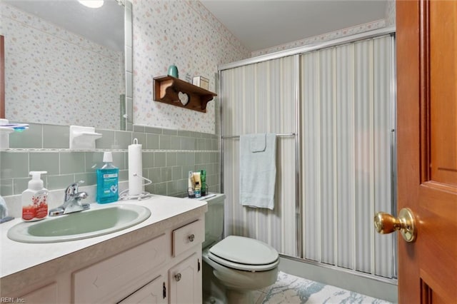 bathroom with vanity, a shower stall, toilet, and wallpapered walls