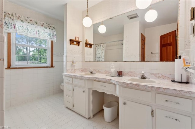 full bathroom featuring double vanity, a shower with curtain, tile walls, and a sink