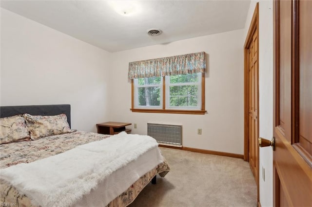 bedroom with baseboards, visible vents, light carpet, and radiator heating unit