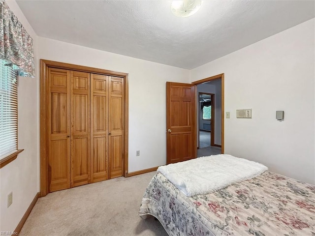 bedroom featuring baseboards, light colored carpet, multiple windows, and a closet