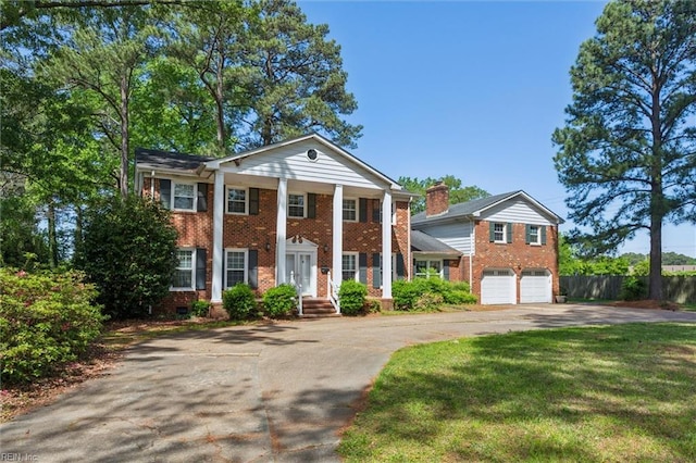 greek revival inspired property featuring concrete driveway, brick siding, fence, and a garage