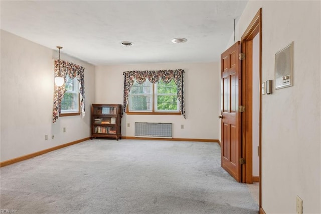 empty room with baseboards, radiator, and light carpet