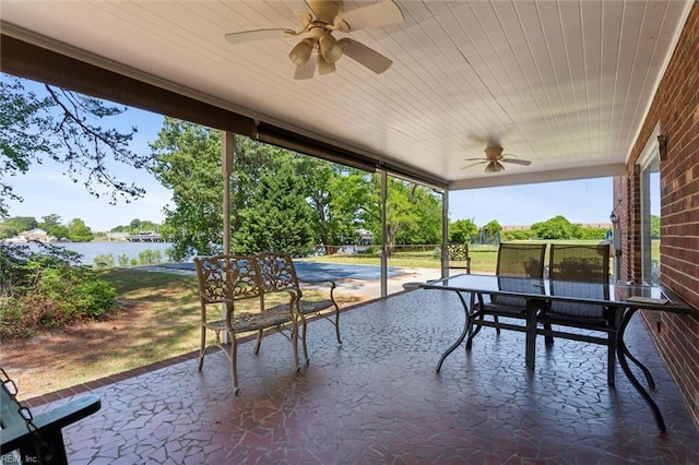 view of patio / terrace featuring a water view, a ceiling fan, and outdoor dining space