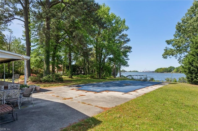view of pool with a water view, a patio area, and a yard