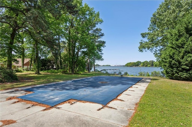 view of swimming pool with a lawn and a water view
