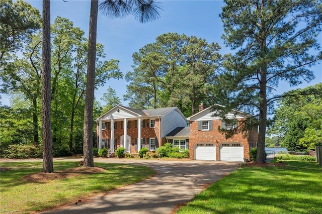 neoclassical home featuring a garage, a front lawn, brick siding, and aphalt driveway