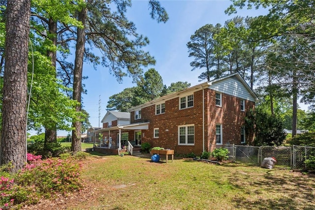 back of house with fence, a yard, and brick siding