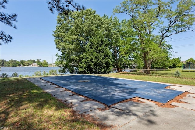 view of pool featuring a lawn, a water view, a fenced backyard, and a patio area