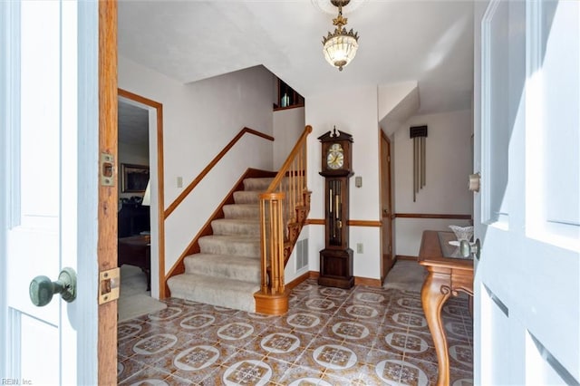 foyer entrance featuring stairs, baseboards, and visible vents