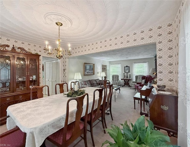 dining room with wallpapered walls, a notable chandelier, and light carpet