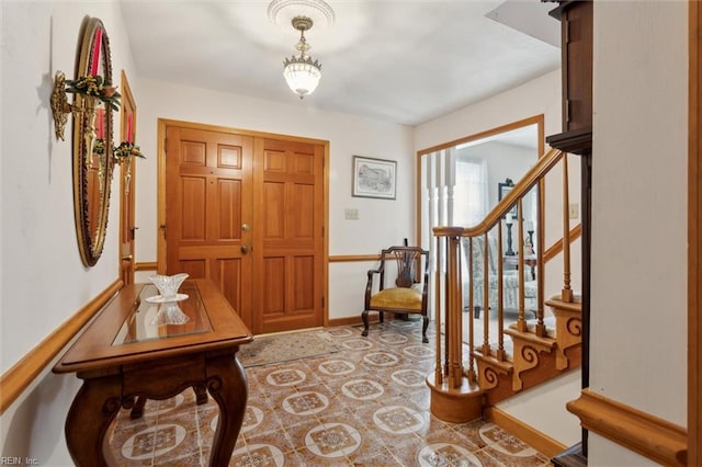 foyer entrance with stairway and baseboards