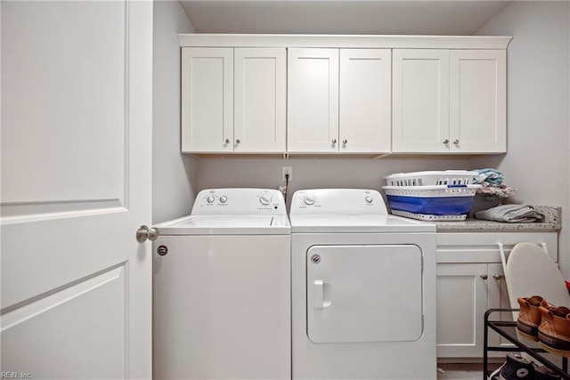 clothes washing area featuring washing machine and clothes dryer and cabinet space