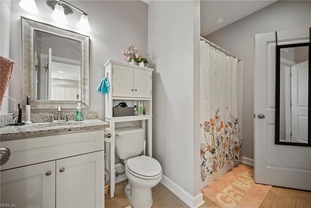 bathroom featuring vanity, toilet, a shower with shower curtain, baseboards, and wood finished floors