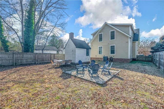 back of property with a fenced backyard, a patio, cooling unit, and an outdoor fire pit