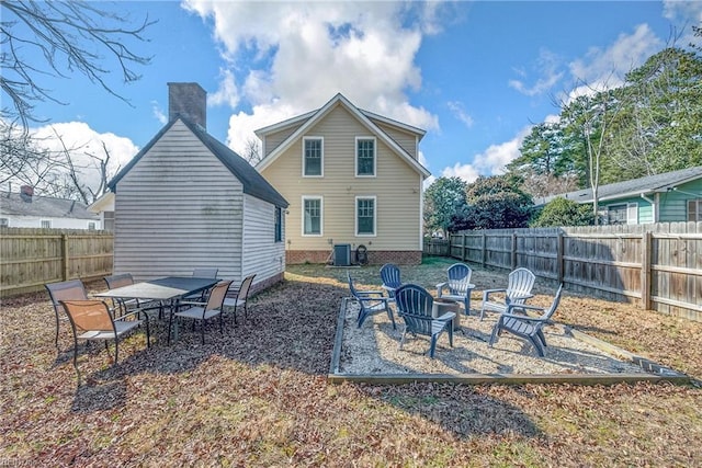 back of property featuring a fenced backyard, a chimney, and central AC