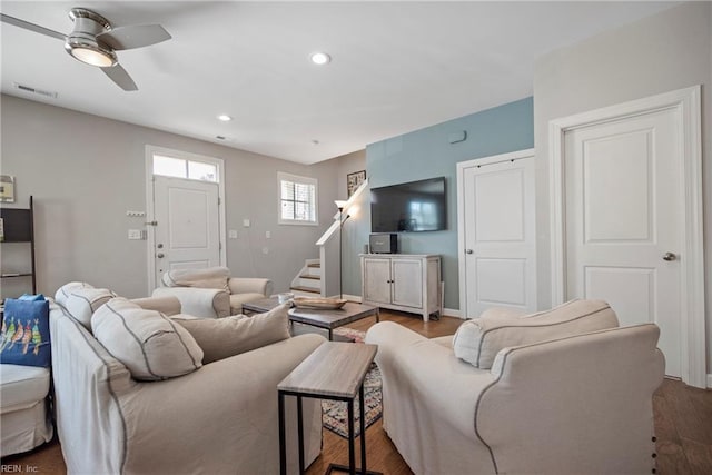 living area featuring visible vents, stairs, wood finished floors, baseboards, and ceiling fan