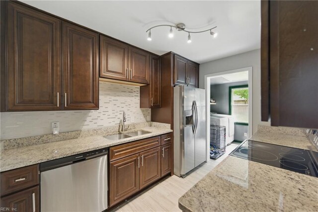 kitchen featuring a sink, appliances with stainless steel finishes, tasteful backsplash, and light stone counters