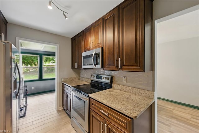 kitchen with baseboards, decorative backsplash, stainless steel appliances, and light wood-style flooring