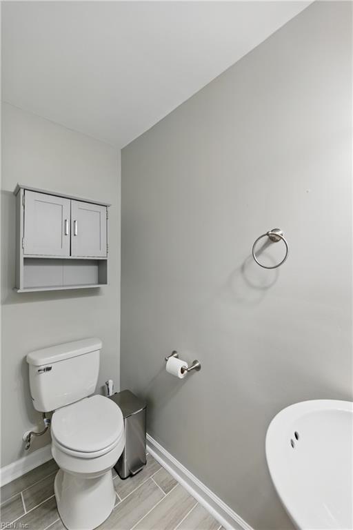 bathroom featuring baseboards, wood finish floors, and toilet