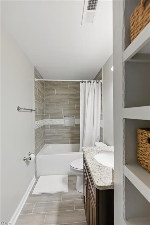 bathroom with visible vents, vanity, baseboards, toilet, and shower / tub combo with curtain