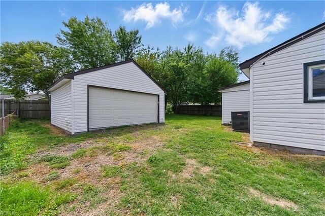 view of yard with a detached garage, fence, an outdoor structure, and central AC unit