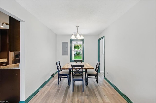 dining area with baseboards, light wood-style flooring, electric panel, and a notable chandelier