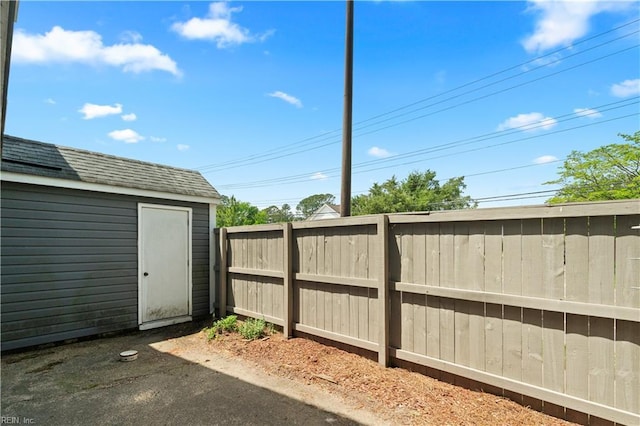 view of yard with fence, an outdoor structure, and a storage unit
