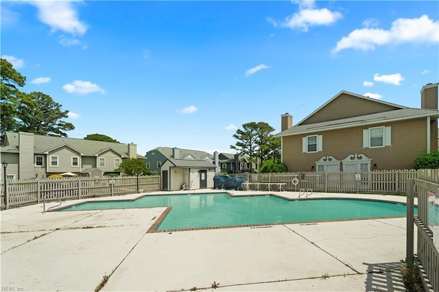 community pool with a residential view, a patio area, and fence
