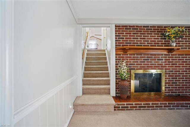 stairway with carpet floors and a brick fireplace
