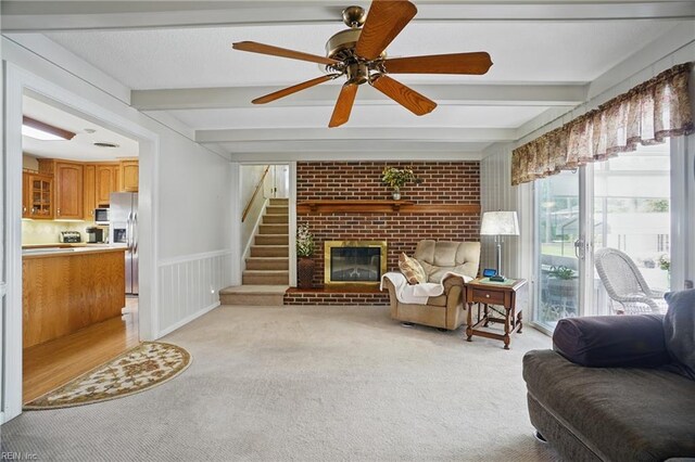 living area featuring beamed ceiling, a ceiling fan, brick wall, and light carpet